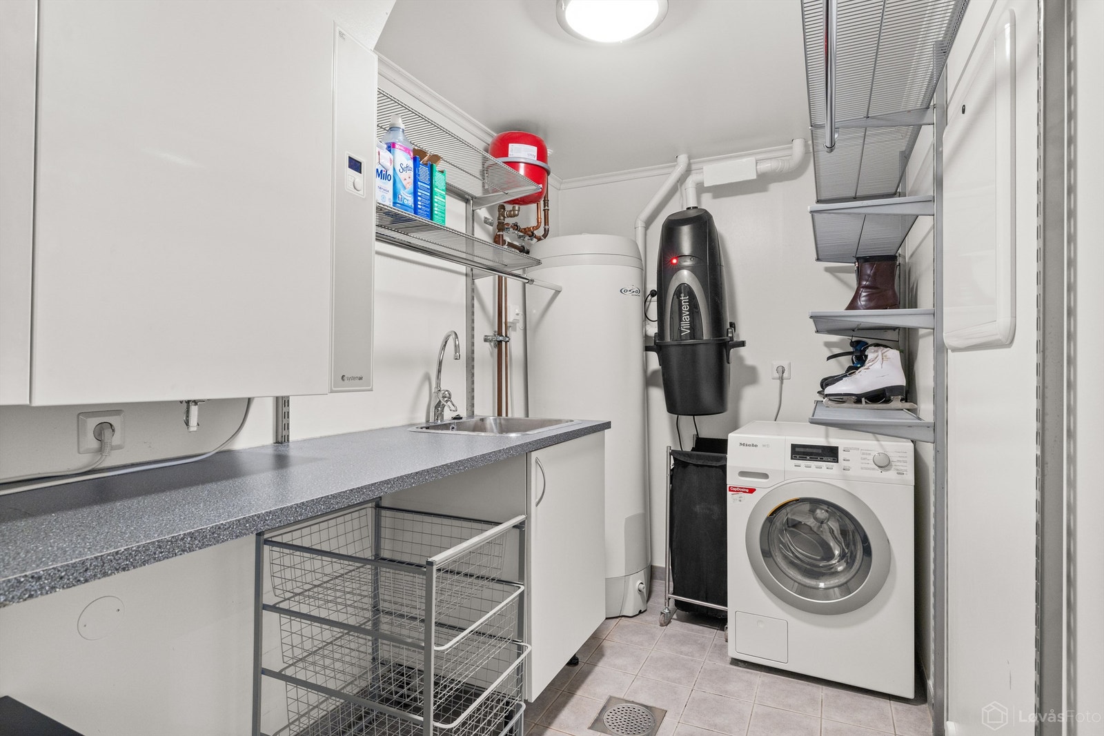 Praktisk vaskerom med flislagt gulv med gulvvarme. Boligens tekniske installasjoner er samlet her, inkludert bl.a. aggregat for balansert ventilasjon og sentralstøvsuger Galleribilde