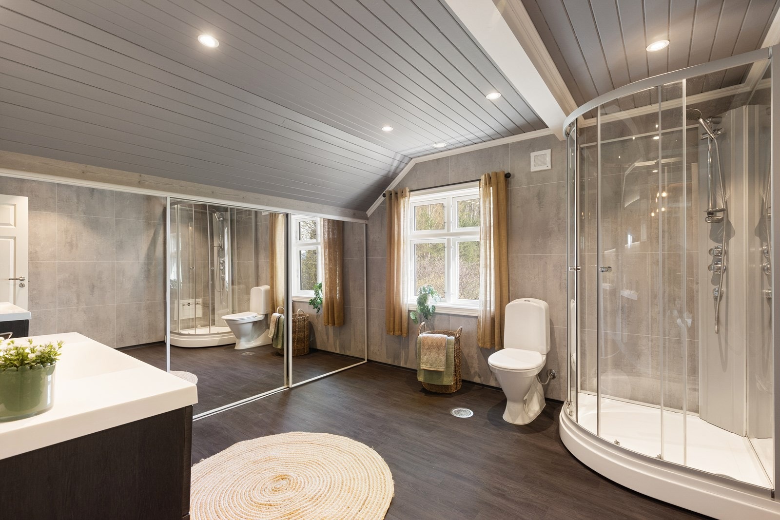 Badet på loftet er også fra 2019, og har vinylbelegg på gulv og panel/ baderomsplater på vegger. Her er det dusjkabinett, toalett og innredning med heldekkende vask, underskuffer med slette fronter og speil. Galleribilde