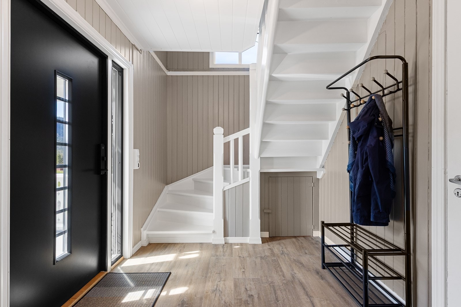Innbydende hall med malt tretrapp til loftsetasjen. Ytterdøren er fra 2019. Her er det varmekabler i gulv. Galleribilde
