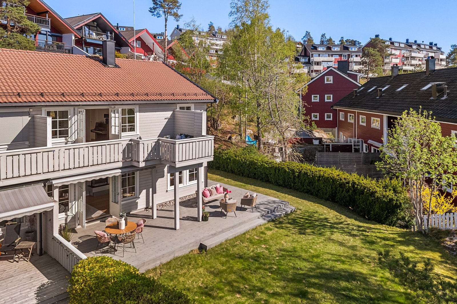 Tomten rundt huset er pent opparbeidet med gressplen og variert beplantning Galleribilde