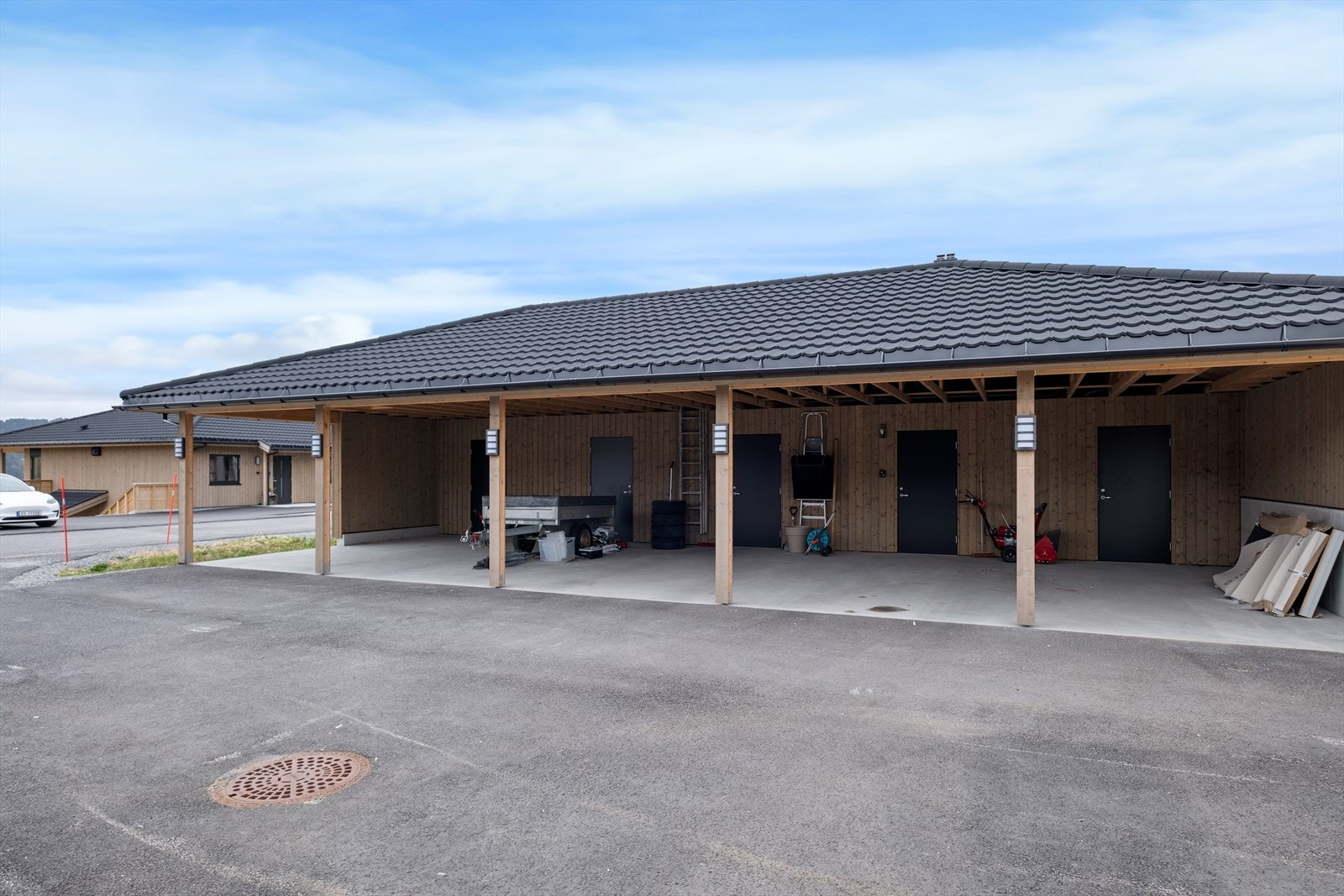 Parkering i carport. Det er lagt trekkerør fra carporten til leiligheten for installasjon av elbillader. Det er også en bod i bakkant av carporten. Galleribilde