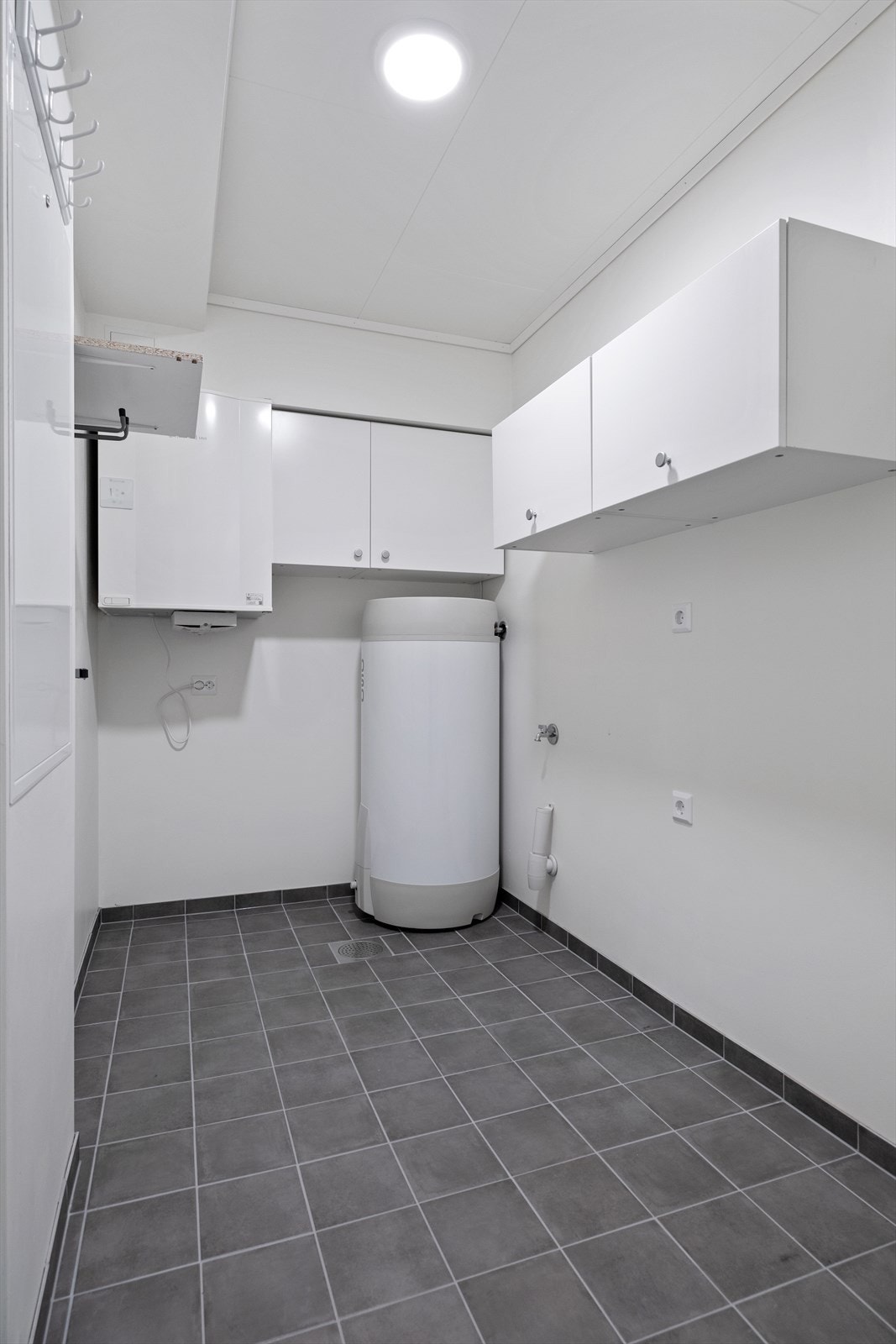 Flislagt bod med varmtvannsbereder, balansert ventilasjon, opplegg for vaskemaskin og sikringsskap. Galleribilde