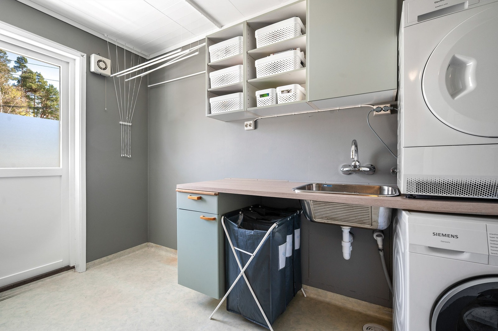 Praktisk vaskerom med opplegg for vaskemaskin, god lagringsplass og egen utgang. Galleribilde