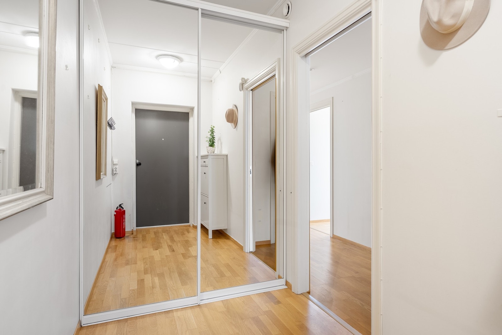 Velkommen inn i en lys entré med skyvedørsgarderobe med speildører som åpner rommet og gir ryddig oppbevaring av yttertøy Galleribilde