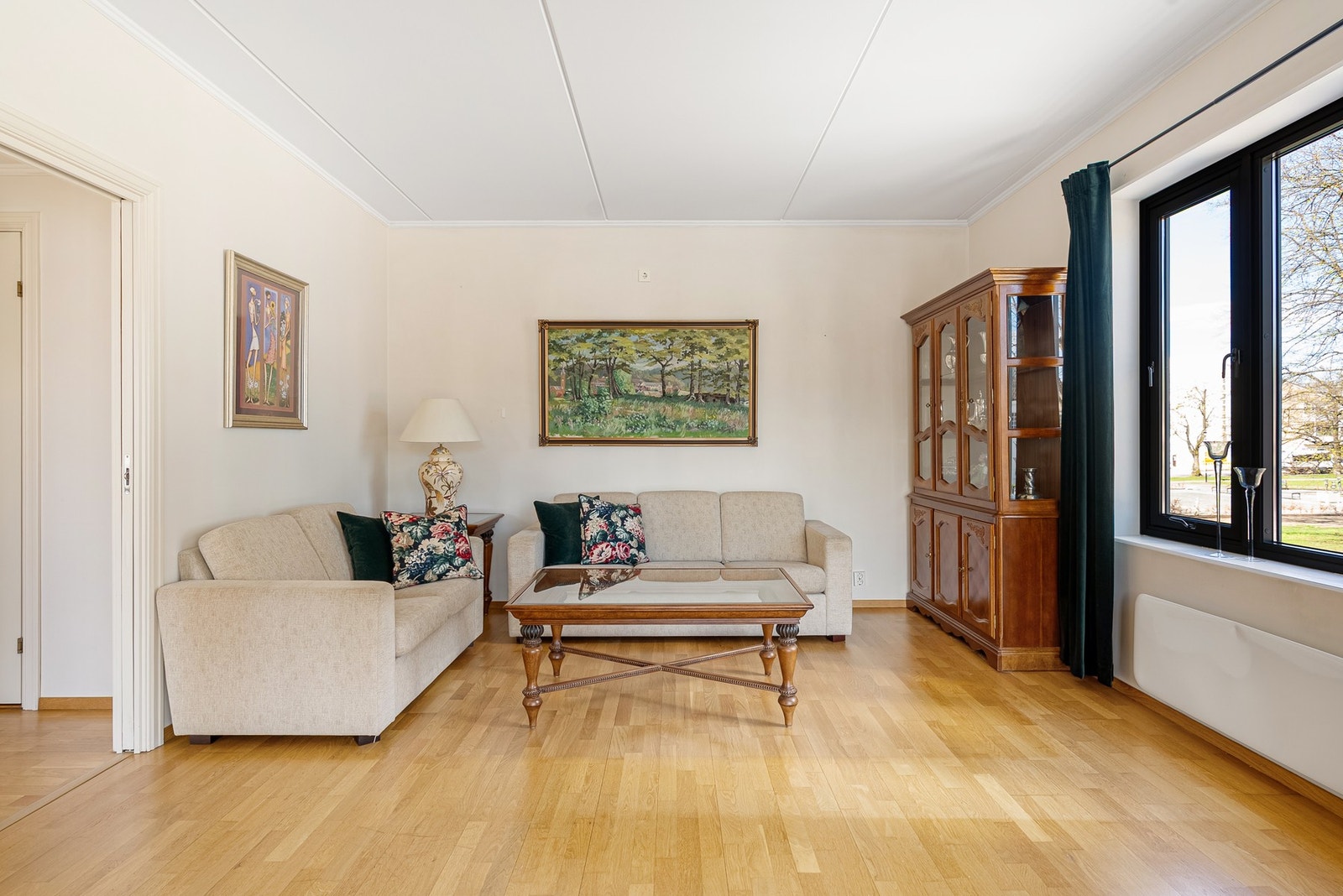 Et lyst og åpent rom med plass til romslig sofa og parkett på gulvet som gir et helhetlig og stilrent uttrykk Galleribilde