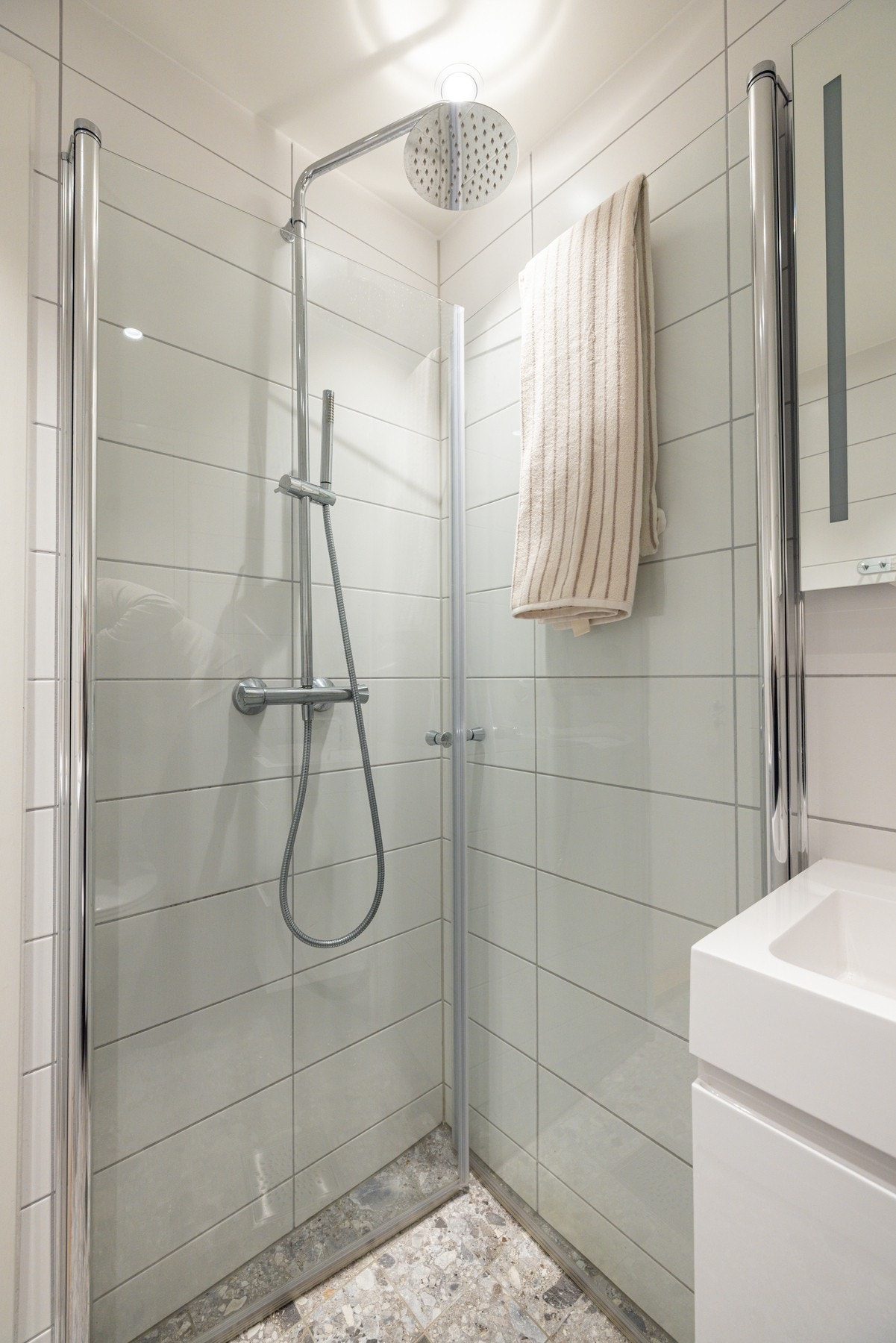 Badet har varmekabler på gulvet, moderne innredning, dusjnisje med svingdører og opplegg for vaskemaskin. Galleribilde