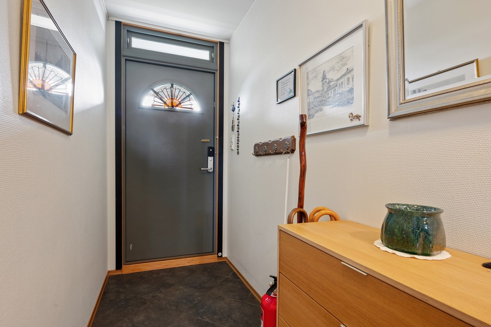 Man ønskes velkommen inn i en lys og romslig entré/gang som er praktisk innredet med flislagt gulv. Her har man god plass til å henge fra seg yttertøy og sko. Galleribilde