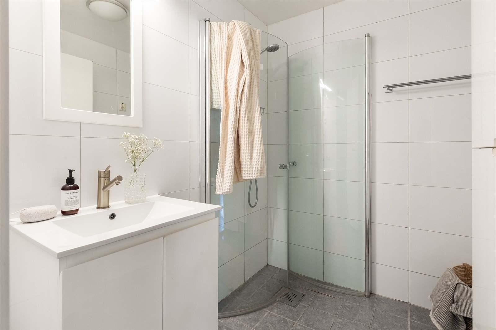 Badet har flislagte overflater, gulvvarme og en praktisk dusjnisje med innfellbare dører. Galleribilde