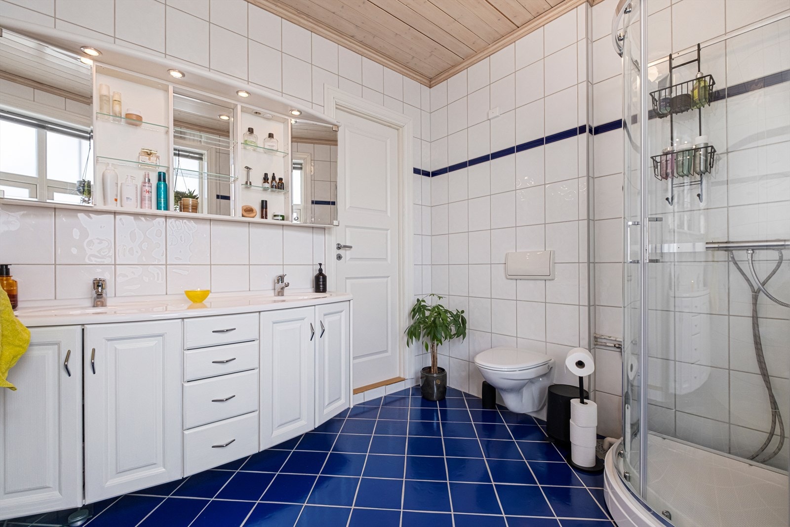 Badet er helfliset og er utstyrt med en romslig innredning med dobbelservant, vegghengt wc og dusjkabinett Galleribilde