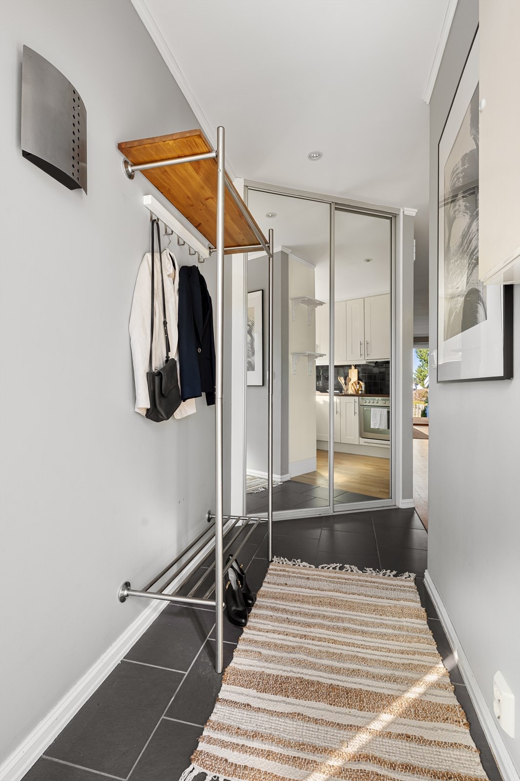 En praktisk skyvedørsgarderobe med speilfronter i entréen gir rikelig med oppbevaringsplass for yttertøy og sko. Galleribilde