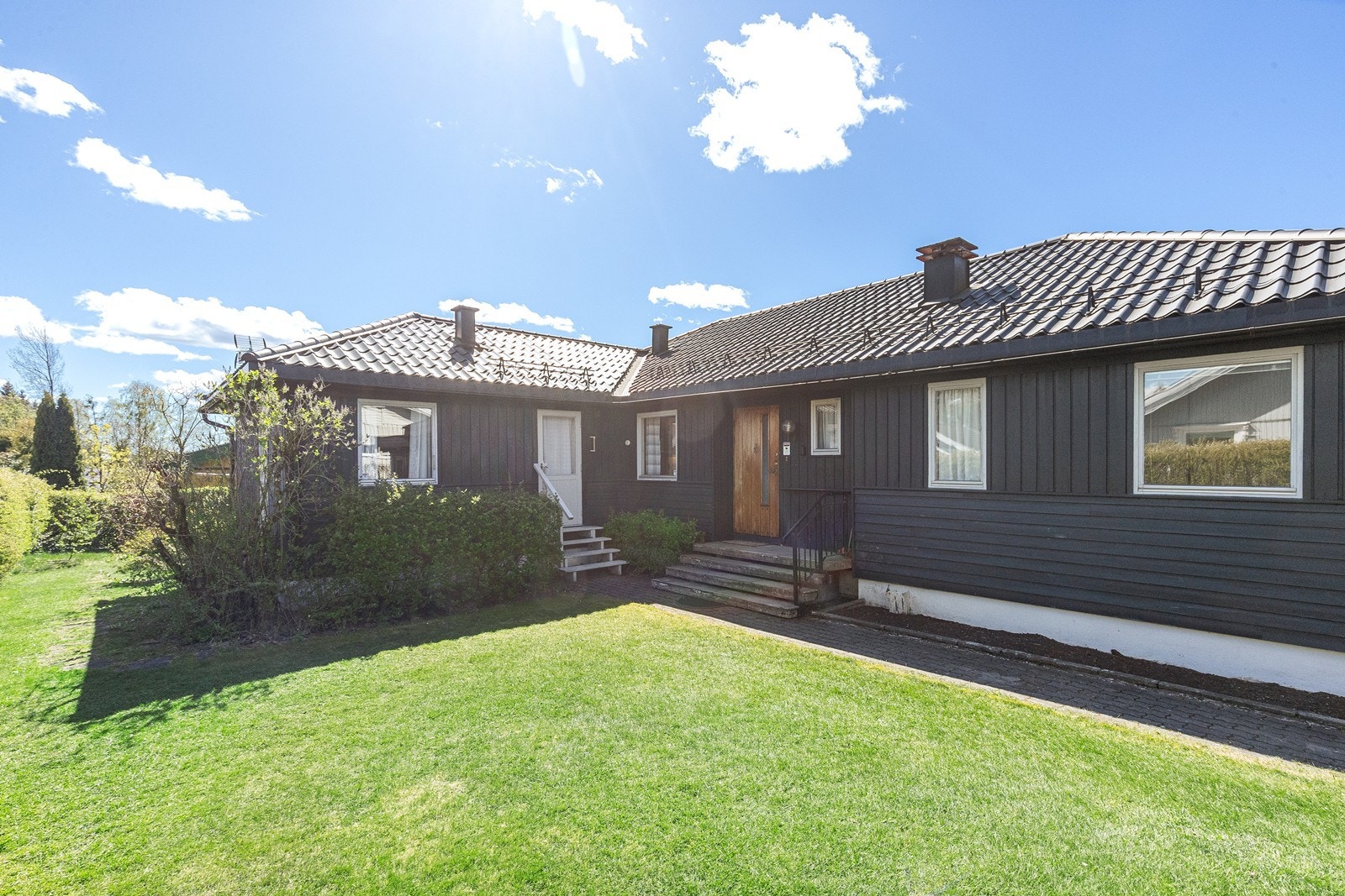 Boligen har en inngangsparti med trapp og overbygg, samt en velstelt hage med plen som omgir huset. Galleribilde