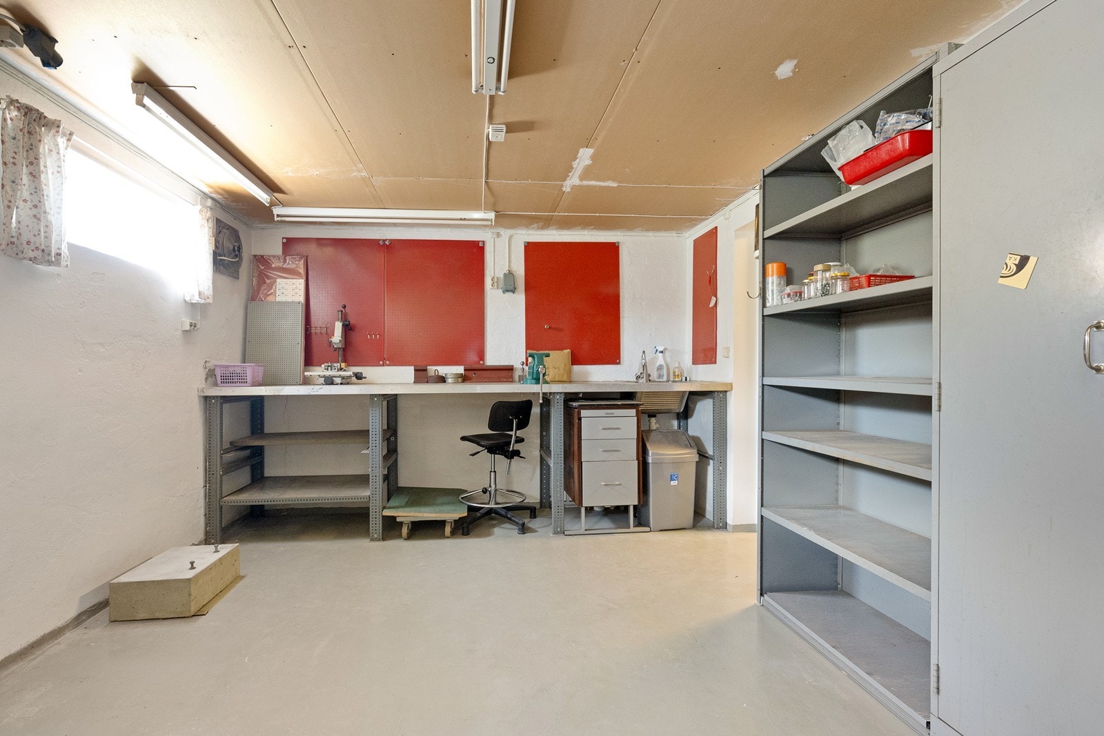 Kjellerrommet inkluderer et verkstedområde med arbeidsbenk og oppbevaringshyller, ideelt for ulike hobbyaktiviteter. Galleribilde