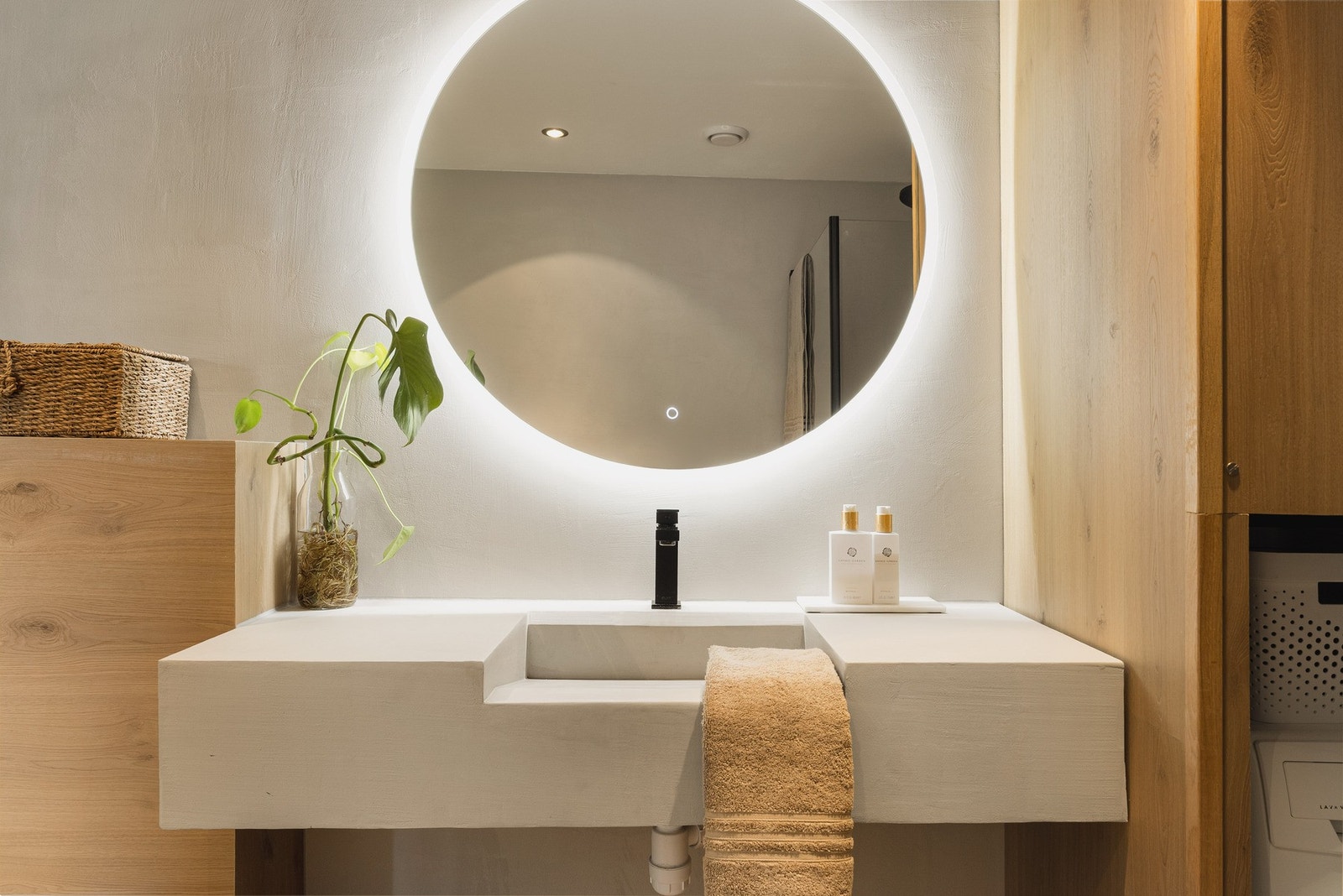 Badet er innredet med vegghengt toalett, dusjhjørne med glassvegger, og en støpt servant med speil og belysning. Galleribilde