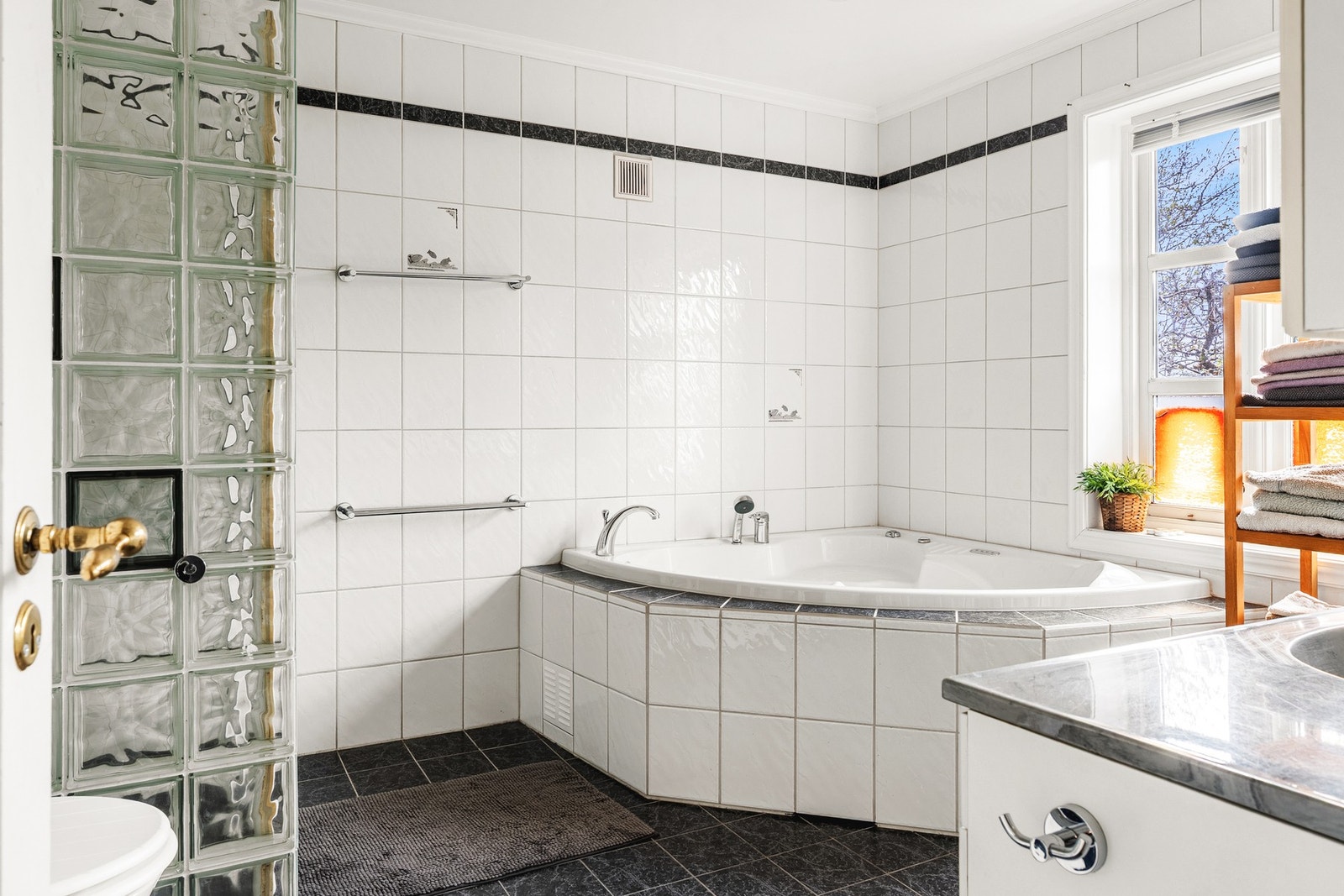 Badet er innredet med bderomsinnredning med dobbel servant, toalett, badekar, dusjhjørne og opplegg for vaskemaskin. Galleribilde