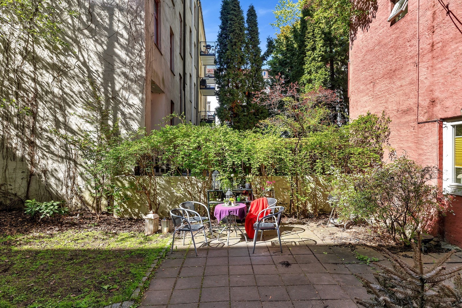 Hyggelig, grønn og frodig bakgård med sittegrupper. Galleribilde