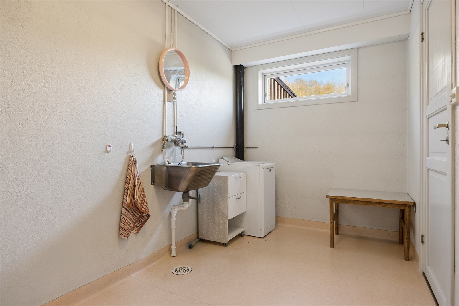 Praktisk vaskerom i sokkeletasjen. Rommet har våtromsbelegg på gulv, opplegg for vaskemaskin og utslagsvask. Galleribilde