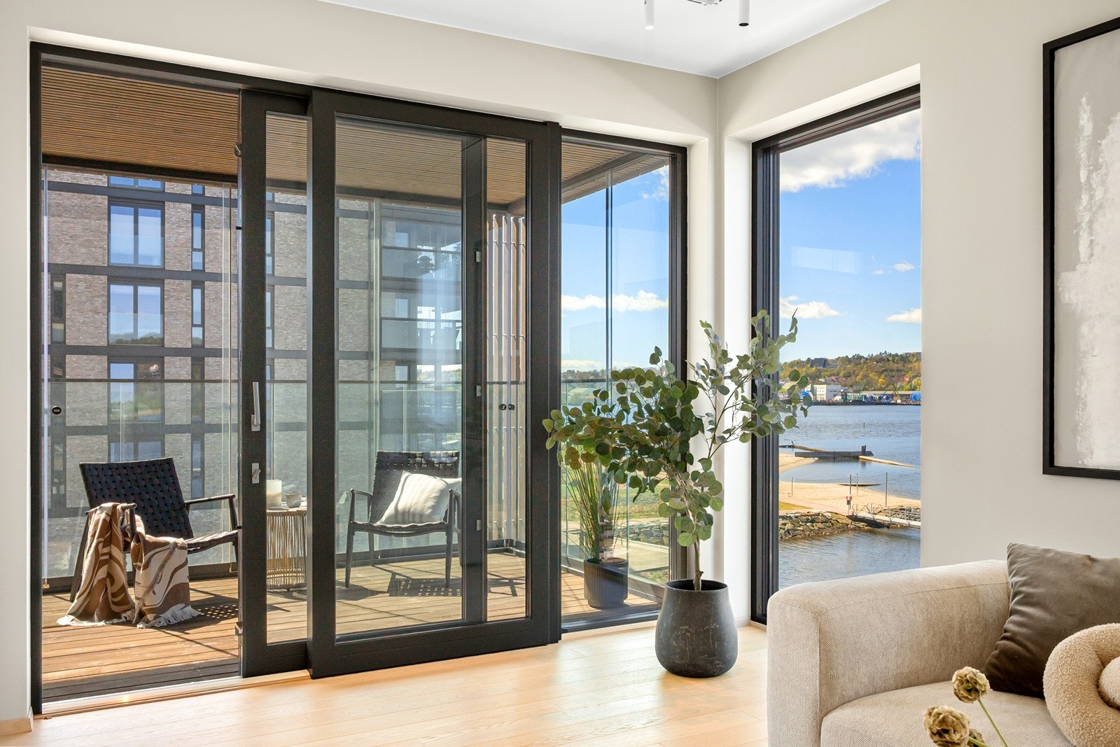 Skyvedør med glassfelt åpner opp mot en sydvestvendt veranda, som sømløst forlenger stuen og inviterer til både avslapning og sosiale stunder. Galleribilde