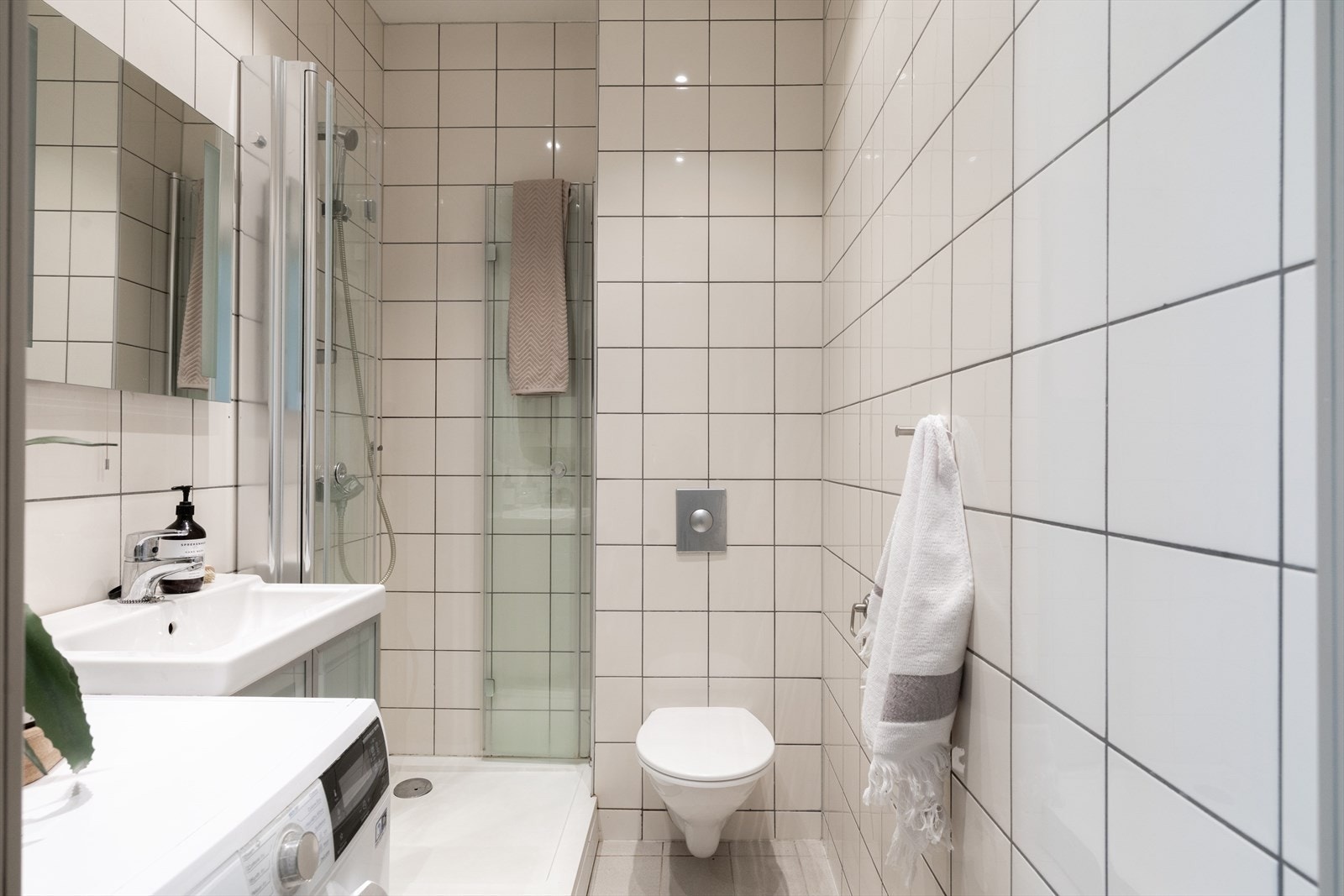 Lyst og pent flislagt bad med varmekabler, downlights i taket og opplegg til vaskemaskin. Galleribilde