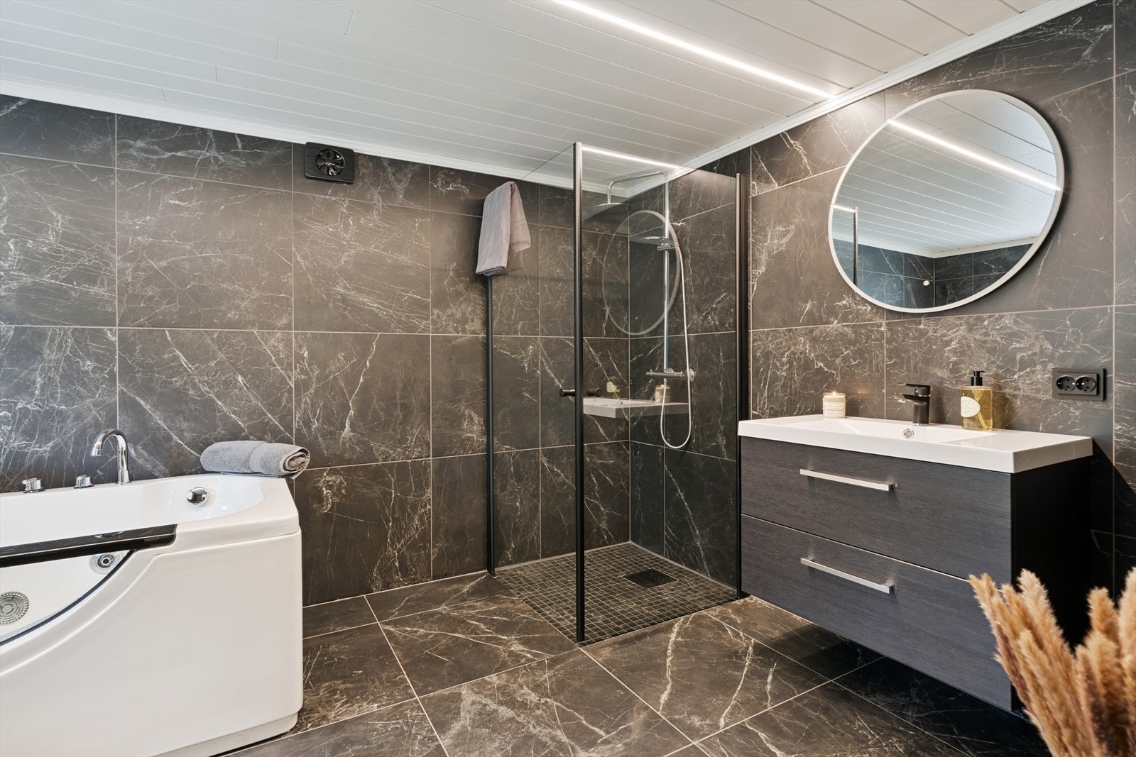 Fra hallen er det dør ned til kjeller hvor man finner et stilfullt bad fra 2020. Badet har store fliser på både vegger og gulv, med unntak av i dusjhjørne hvor det er moasikkliser på gulvet. Varmekabler i gulv. Galleribilde