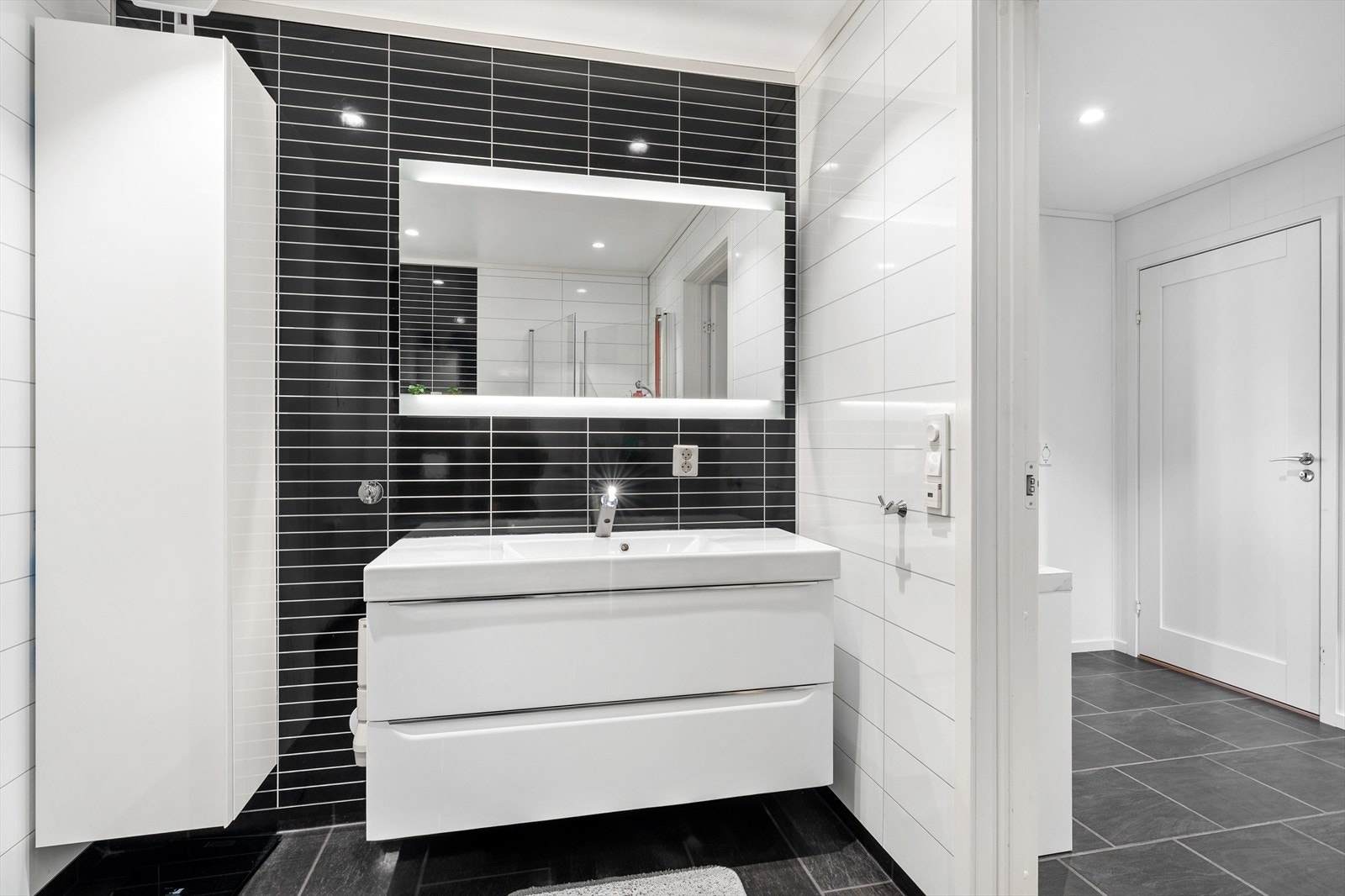 Badet er innredet med servantmøbel, veggmontert toalett og har opplegg for vaskemaskin. Galleribilde