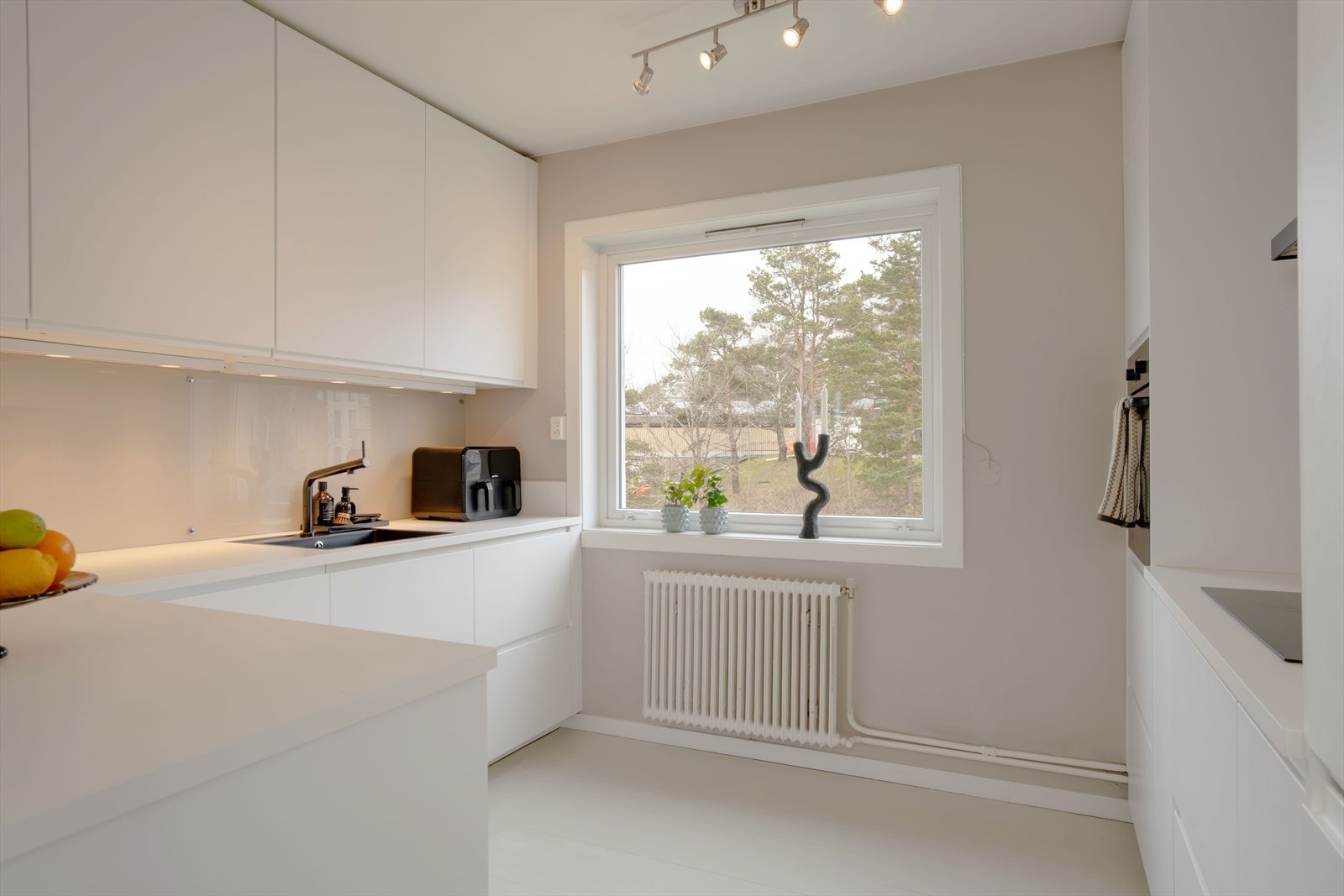 Moderne kjøkken med rikelig benke- og skapplass. Radiatoren under vinduet er koblet til fellesanlegget for vannbåren varme. Galleribilde