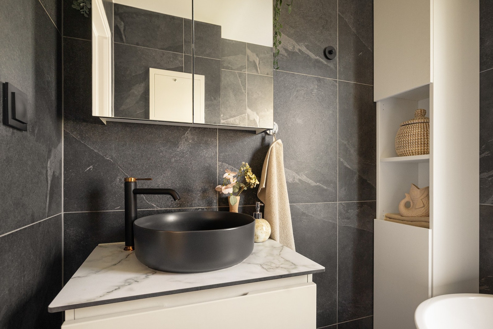 Badet er innredet med en moderne servantseksjon, speilskap og et høyskap for ekstra oppbevaringsplass. Galleribilde