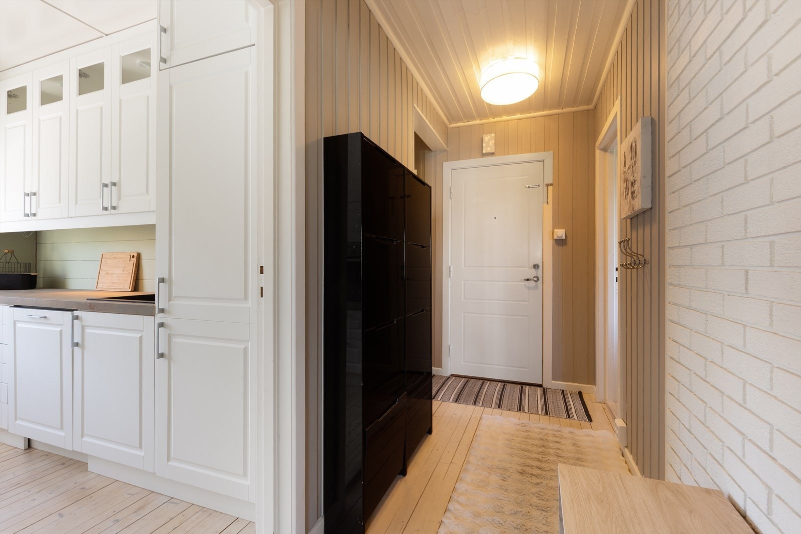 Entréen ønsker velkommen med malte panelvegger og gjennomgående furugulv. Galleribilde