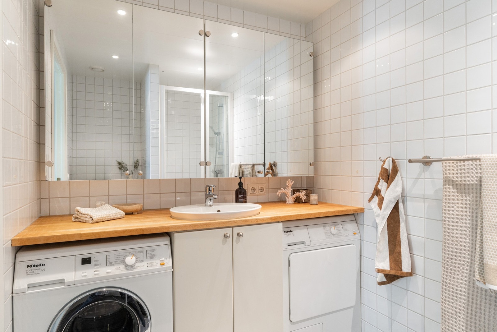 Romslig, flislagt baderom med varmekabler i gulv og downlights i himling Galleribilde