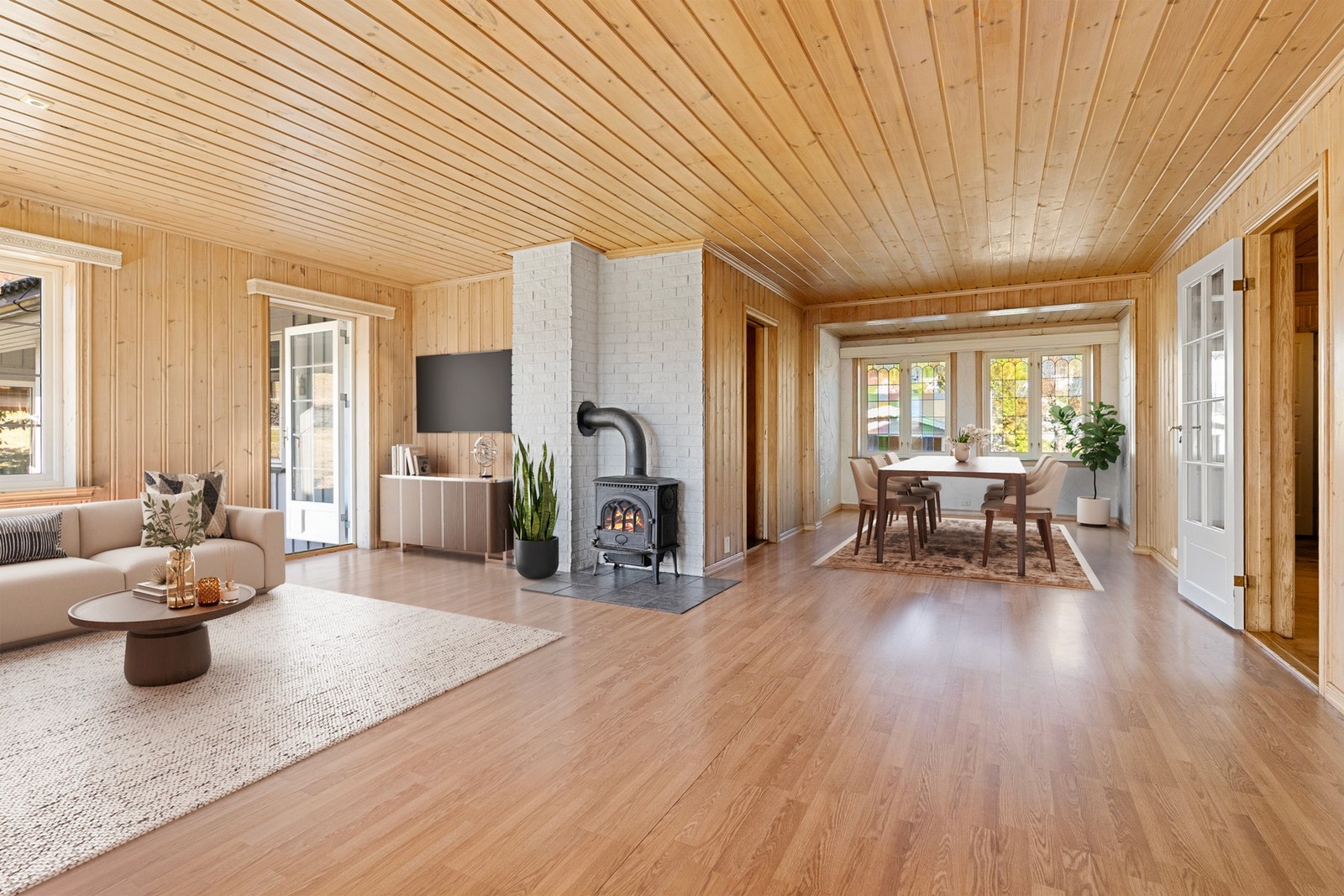 Lys og innbydende stue med store vindusflater som gir godt med naturlig lysinnslipp og en luftig romfølelse. Bildet er digitalt illustrert. Galleribilde