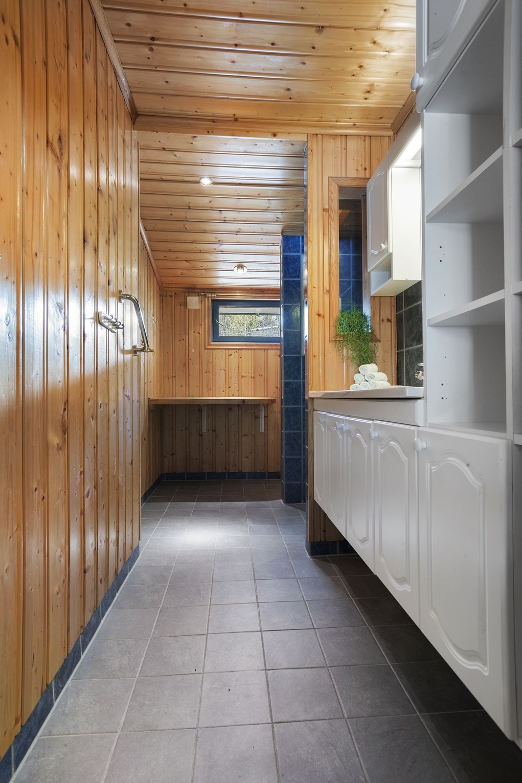 Badet har fliser i dusjnisjen og bak servanten, mens øvrige veggflater er kledd med trepanel og avsluttet med sokkelflis. Galleribilde