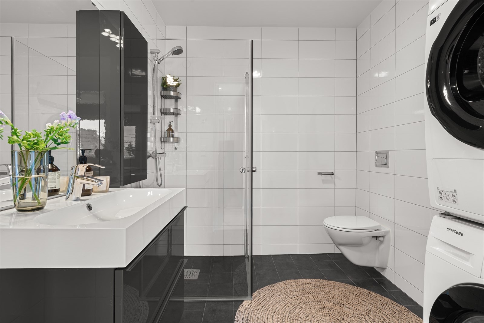 - Badet måler 5,3m² og er innredet med servantmøbel, vegghengt toalett, dusjhjørne med glassdører og opplegg for vaskemaskin - Galleribilde