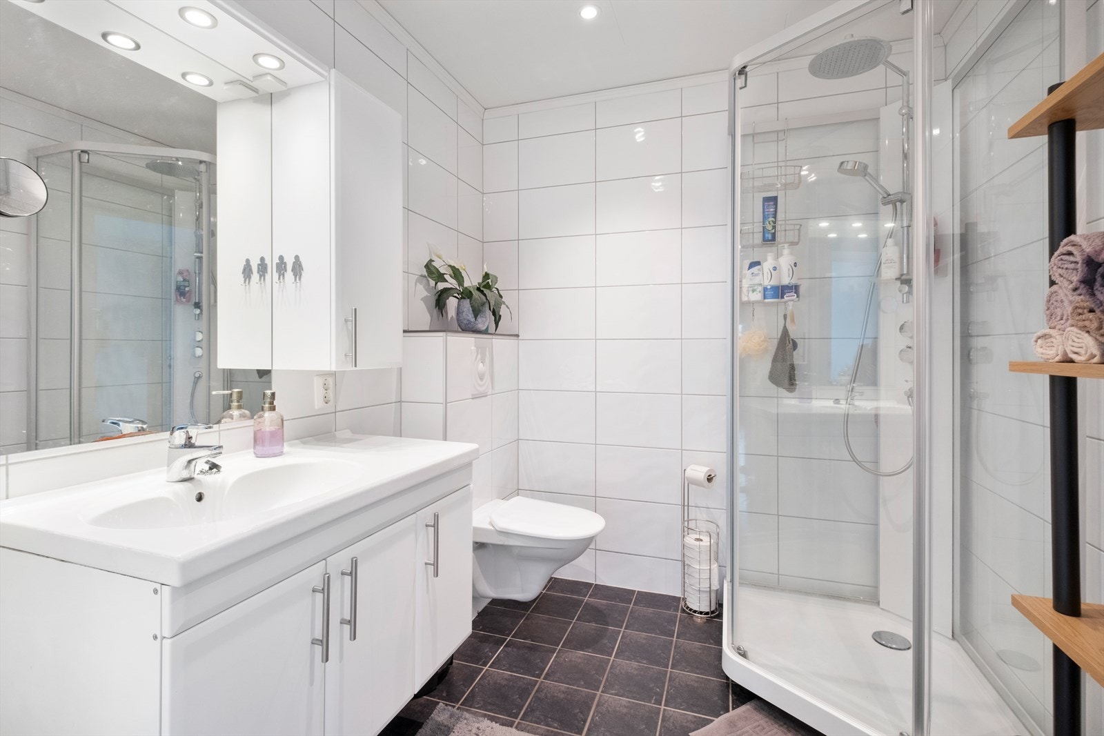 Badet har flislagte gulv og vegger, vegghengt toalett og dusjkabinett. Galleribilde