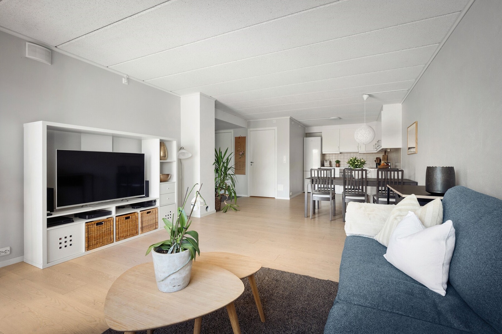 Det er god plass til både sofagruppe og spisebord, og de lyse overflatene kombinert med en gjennomgående planløsning gir boligen et moderne og luftig preg. Galleribilde