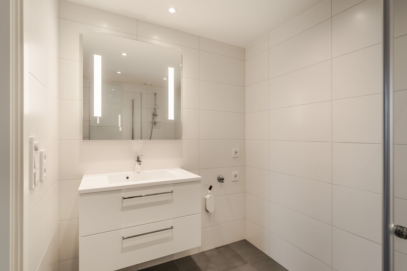 Badet måler ca. 4 m² og er utstyrt med gulvvarme, opplegg for vaskemaskin og moderne innredning. Galleribilde