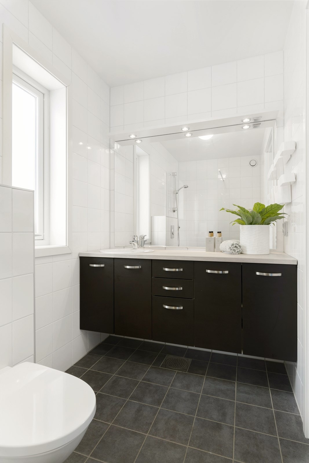 Badet er utstyrt med baderomsinnredningen har mørke fronter og oljet benkeplate med nedfelt servant i underskap. Dette er badet til hovedsoverommet. Galleribilde