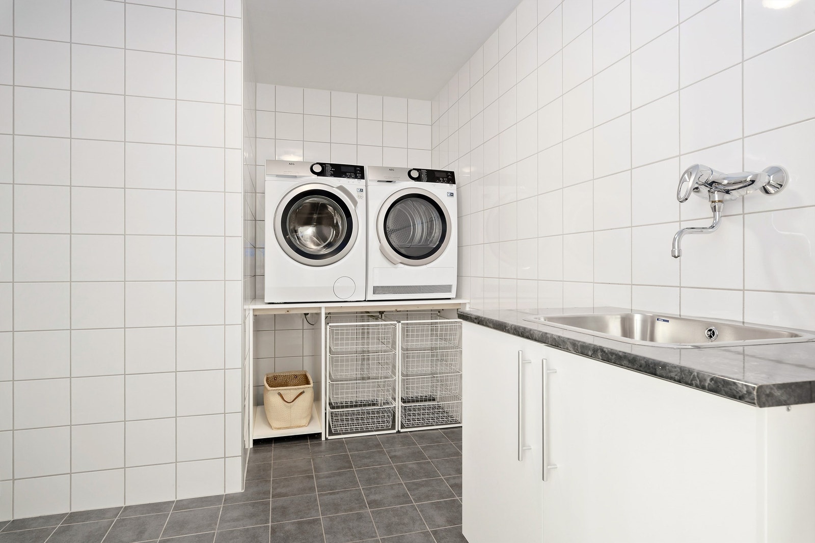 Vaskerom i underetasjen er flislagt med varmekabler på gulv. Det er malte plater i tak. Vaskerommet er utstyrt med benk med underskap og utslagsvask. Galleribilde