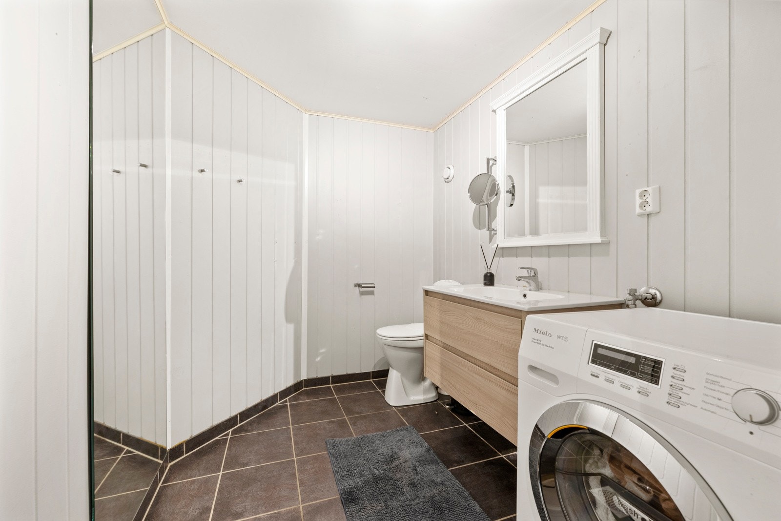 Det andre badet har flislagt gulv og panel på vegger, og er utstyrt med servantmøblement, toalett samt opplegg for vaskemaskin. Begge bad har gulvvarme. Galleribilde
