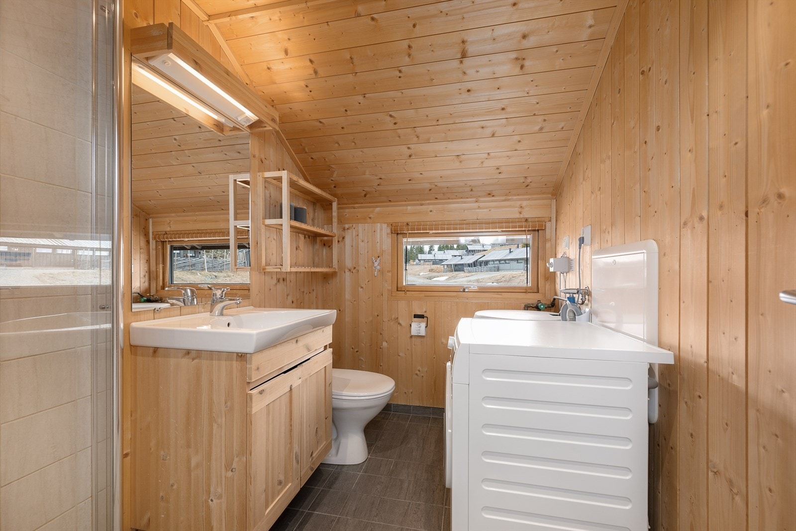 Badet har flislagt gulv med gulvvarme og opplegg for vaskemaskin. Galleribilde