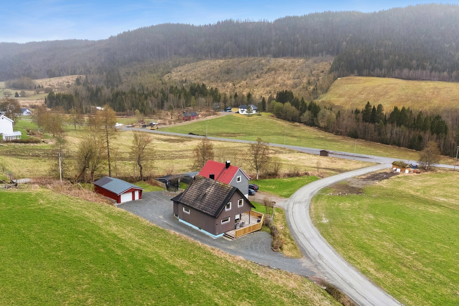 Stor, gruset gårdsplass med rikelig med parkeringsplass og en romslig, frittstående garasje. Galleribilde
