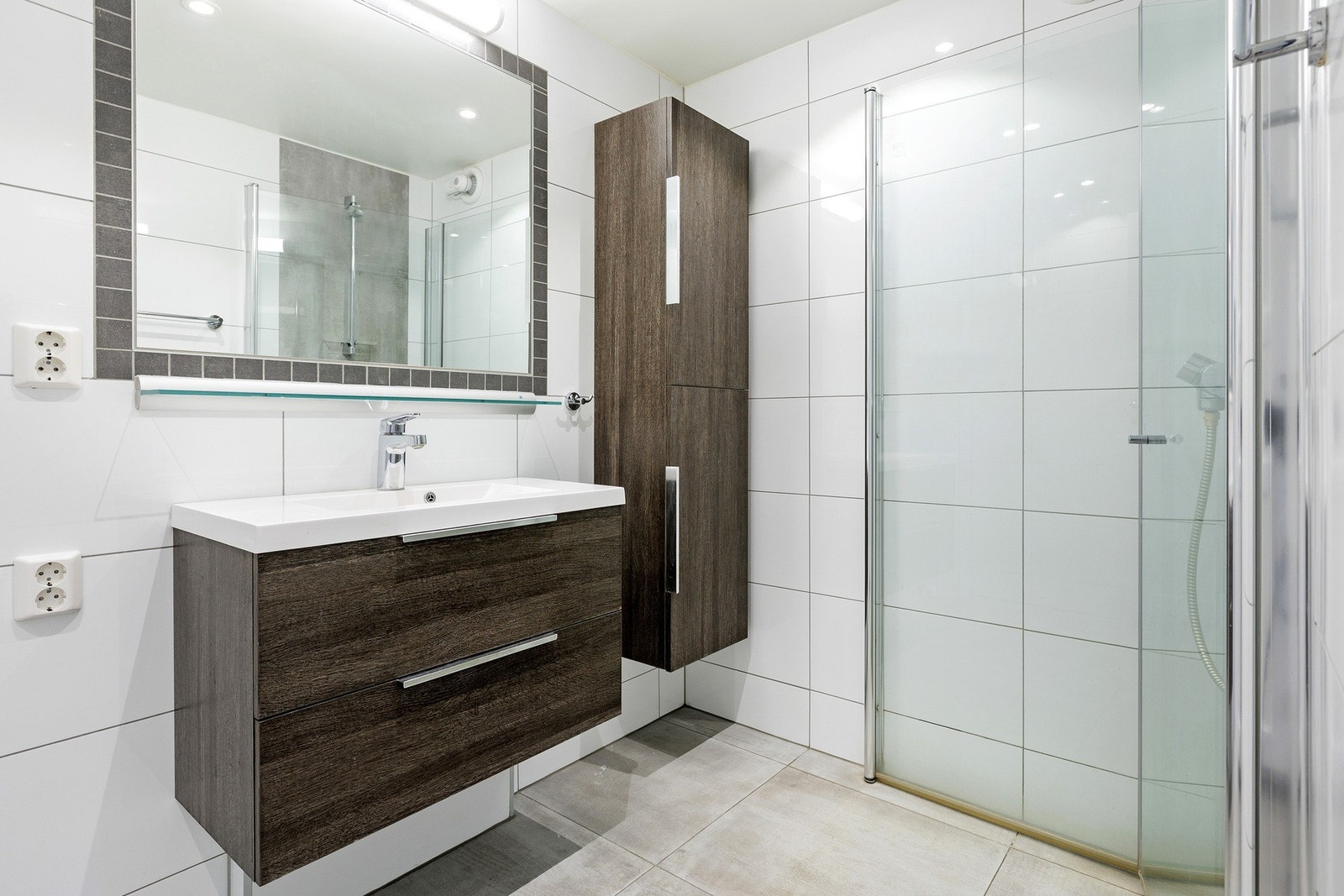 Flislagt bad med moderne uttrykk og praktiske løsninger. Badet har fliser på gulv og vegger, samt malt himling med innfelte downlights. Galleribilde