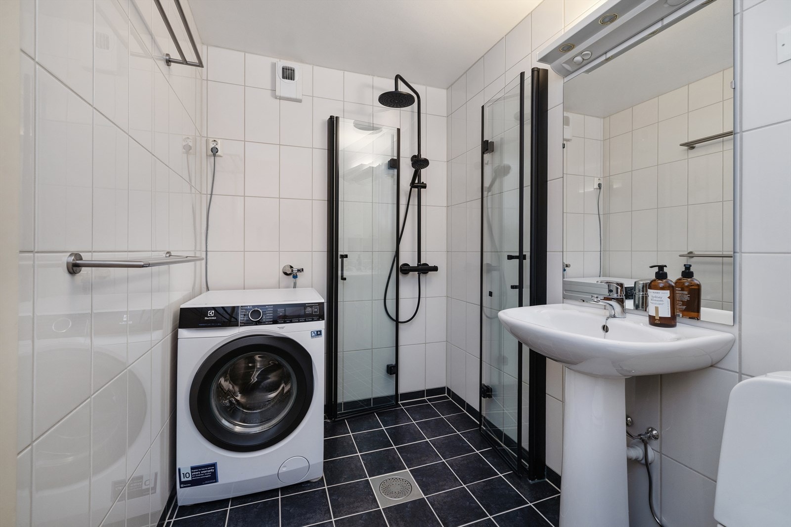 Badet har opplegg for vaskemaskin og et dusjhjørne med glassdører. Dusjopplegg og blandebatteri er fra 2022. Galleribilde