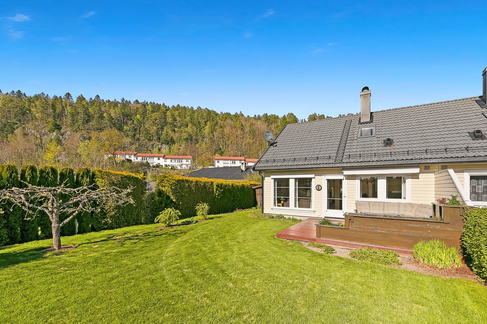 Flat og lettstelt tomt med gode solforhold og hyggelige uteområder. Tomten er pent opparbeidet med stor gressplen, beplantning, prydbusker og hekk som gir et skjermet og privat preg. Galleribilde