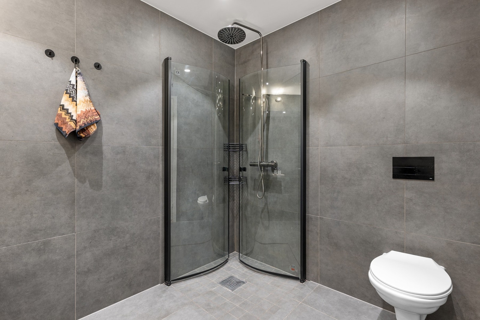 Badet er på Ca. 5 kvm og er utstyrt med varmekabler i gulv, vegghengt toalett og dusjhjørne med innfellbare dører. Galleribilde