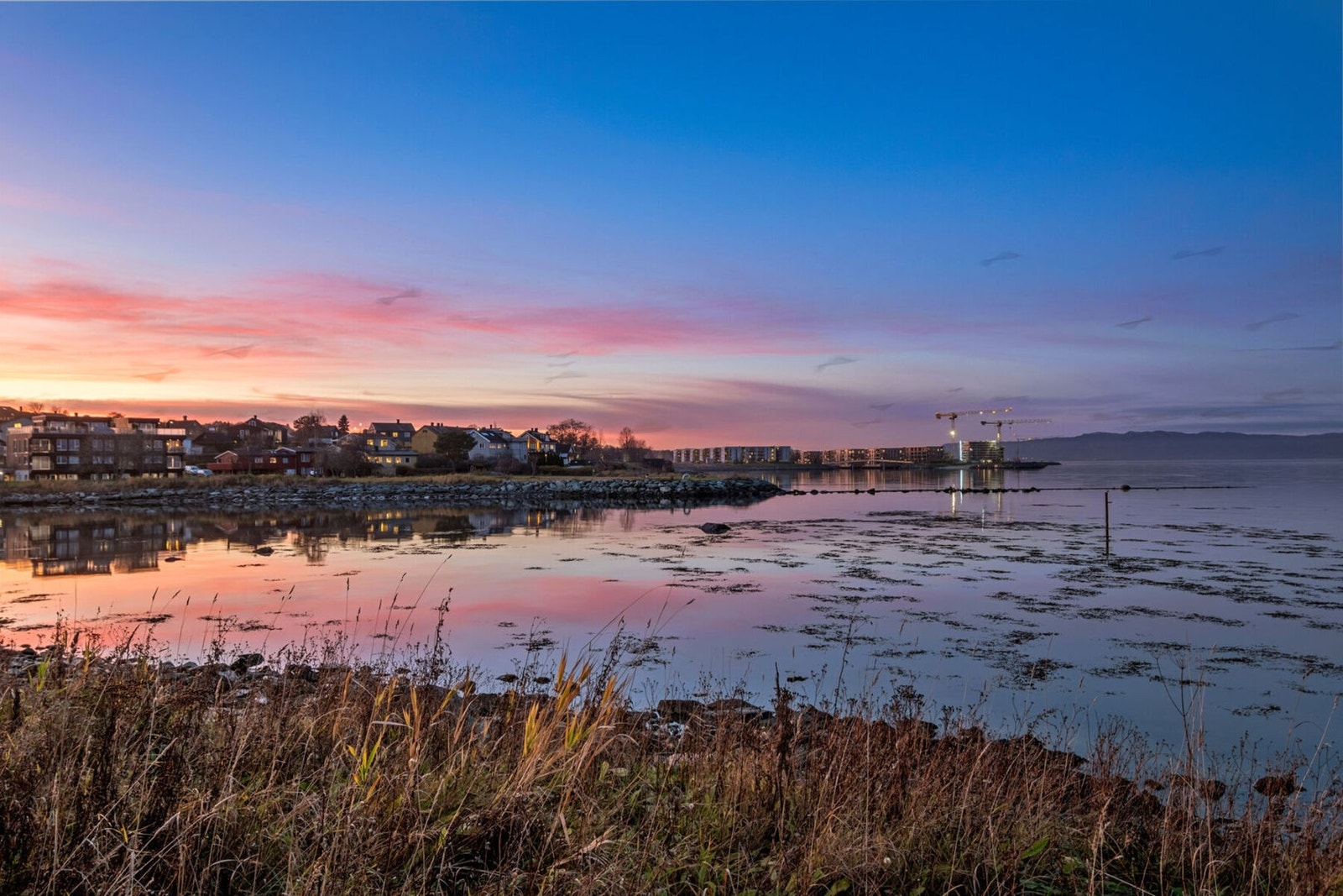 Stemningsbilde fra vannkanten med Grilstad Marina i bakgrunnen. Galleribilde