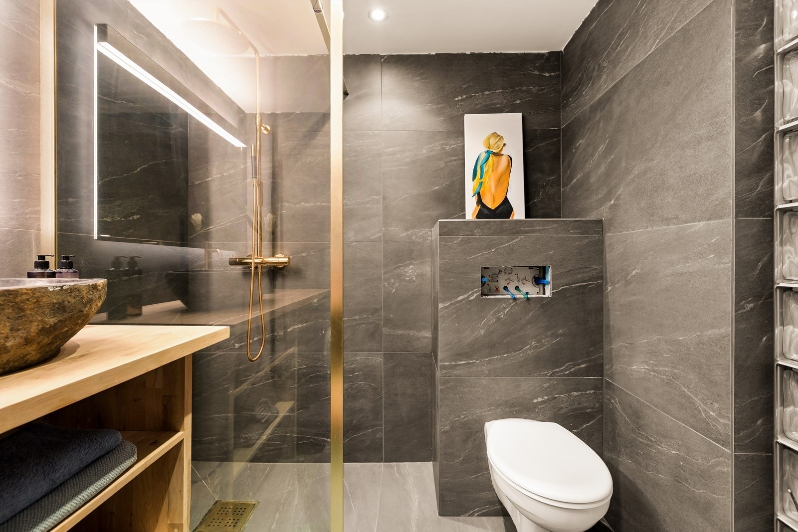Badet har vegghengt toalett og et dusjhjørne med innfellbare glassdører. Galleribilde