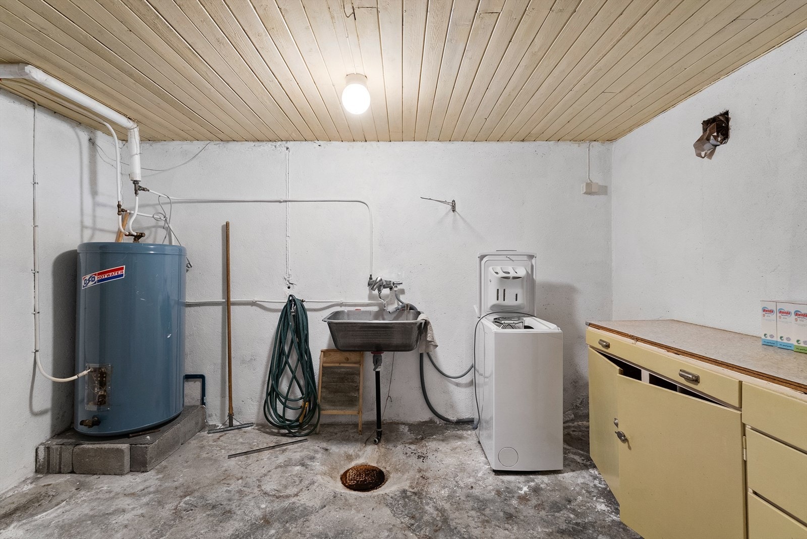 Vaskerom med betonggulv, skyllekar og opplegg for vaskemaskin. Her står også en 200-liters varmtvannsbereder. Galleribilde