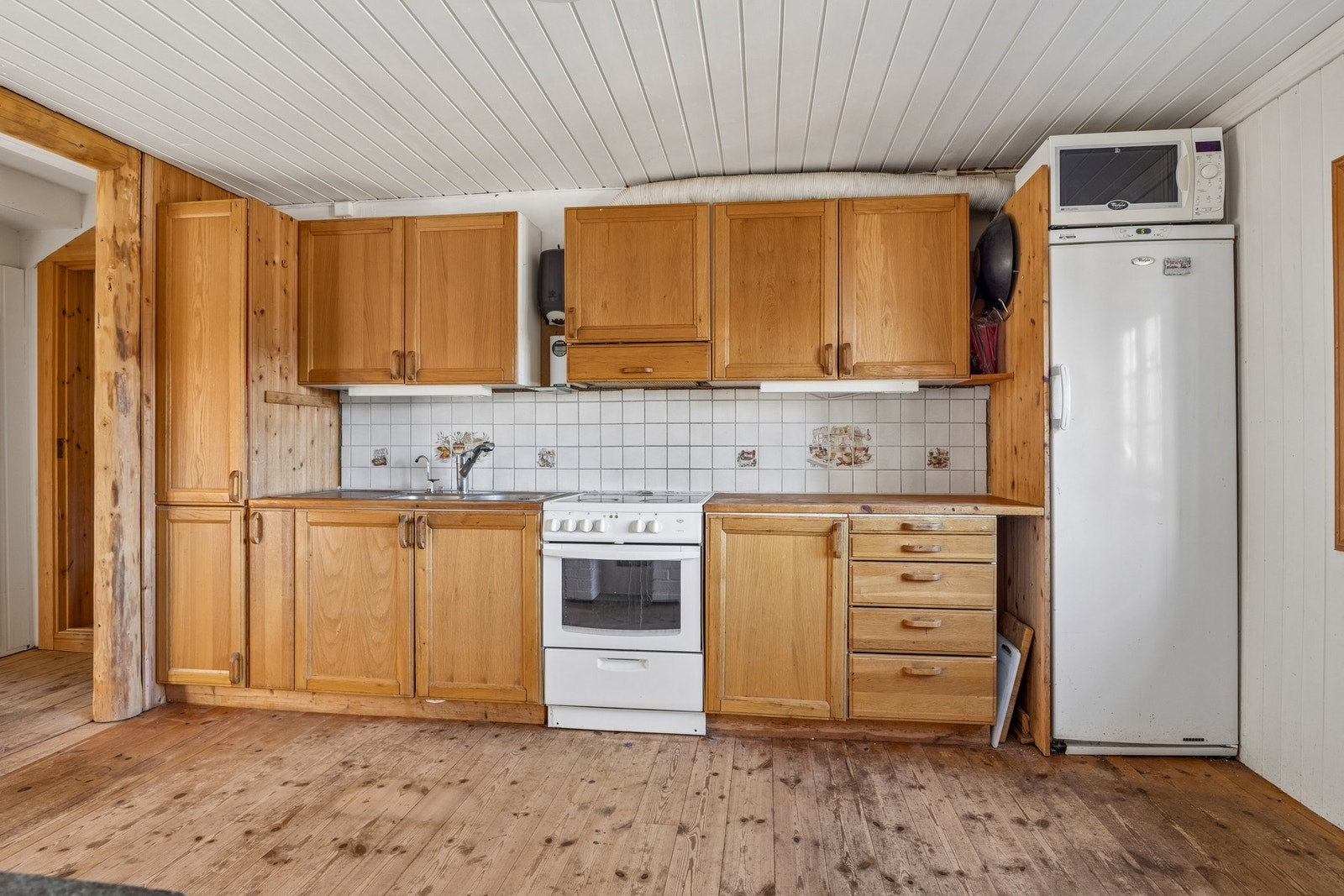 Innredningen har frittstående hvitevarer og kjøkkenventilator med avtrekk ut. Galleribilde