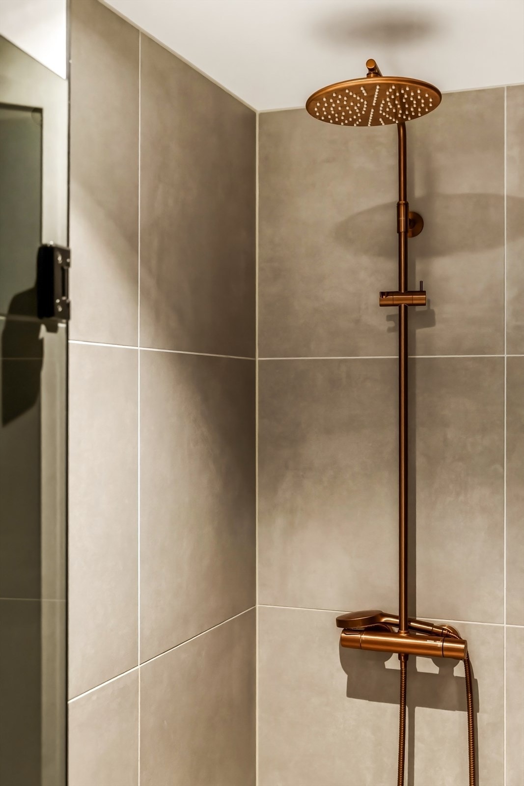 Mørke detaljer og helflisede overflater gir badet et eksklusivt uttrykk. Galleribilde
