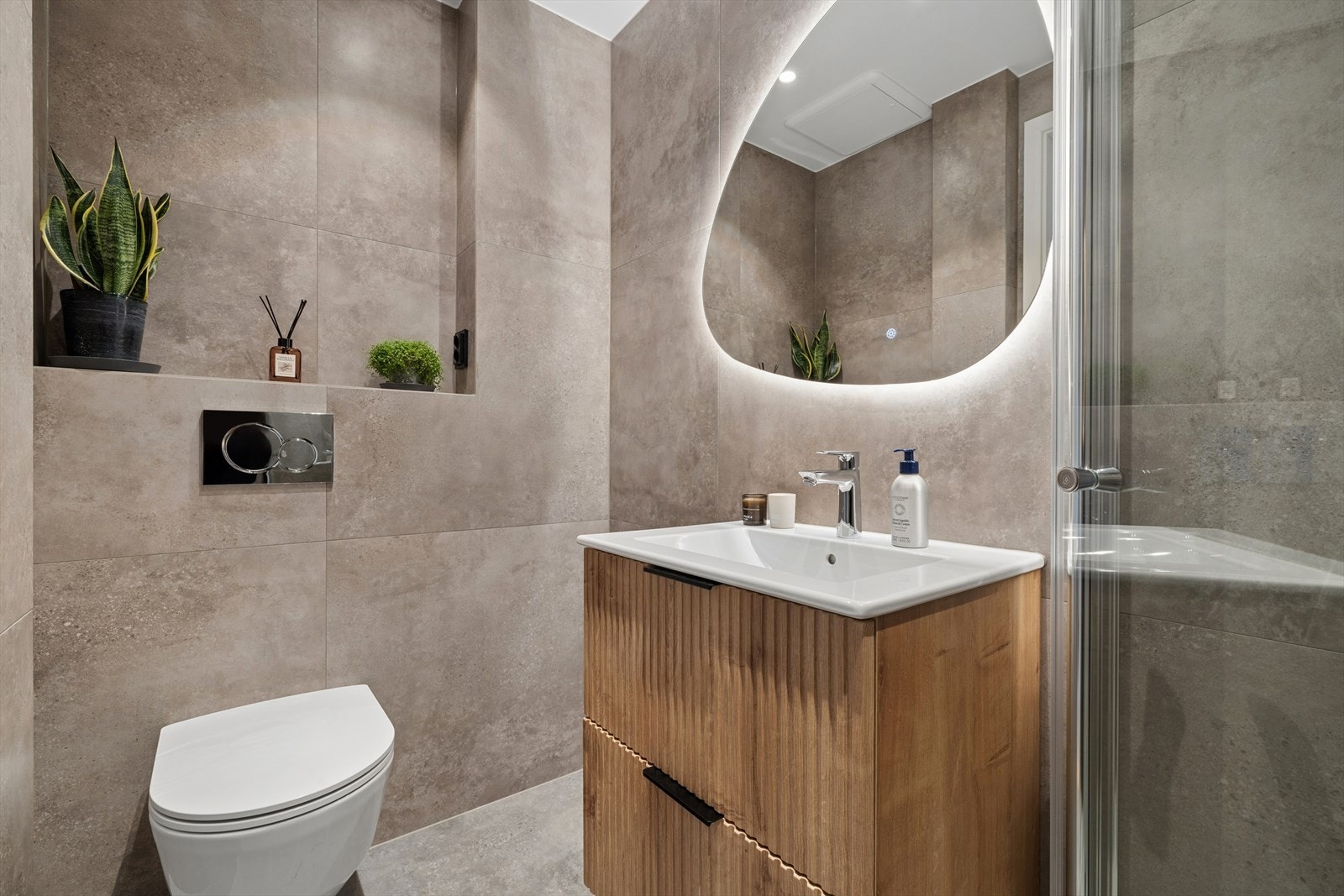 Badet er innredet med dusjnisje, vegghengt toalett, servant med innredning og opplegg for vaskemaskin. Galleribilde