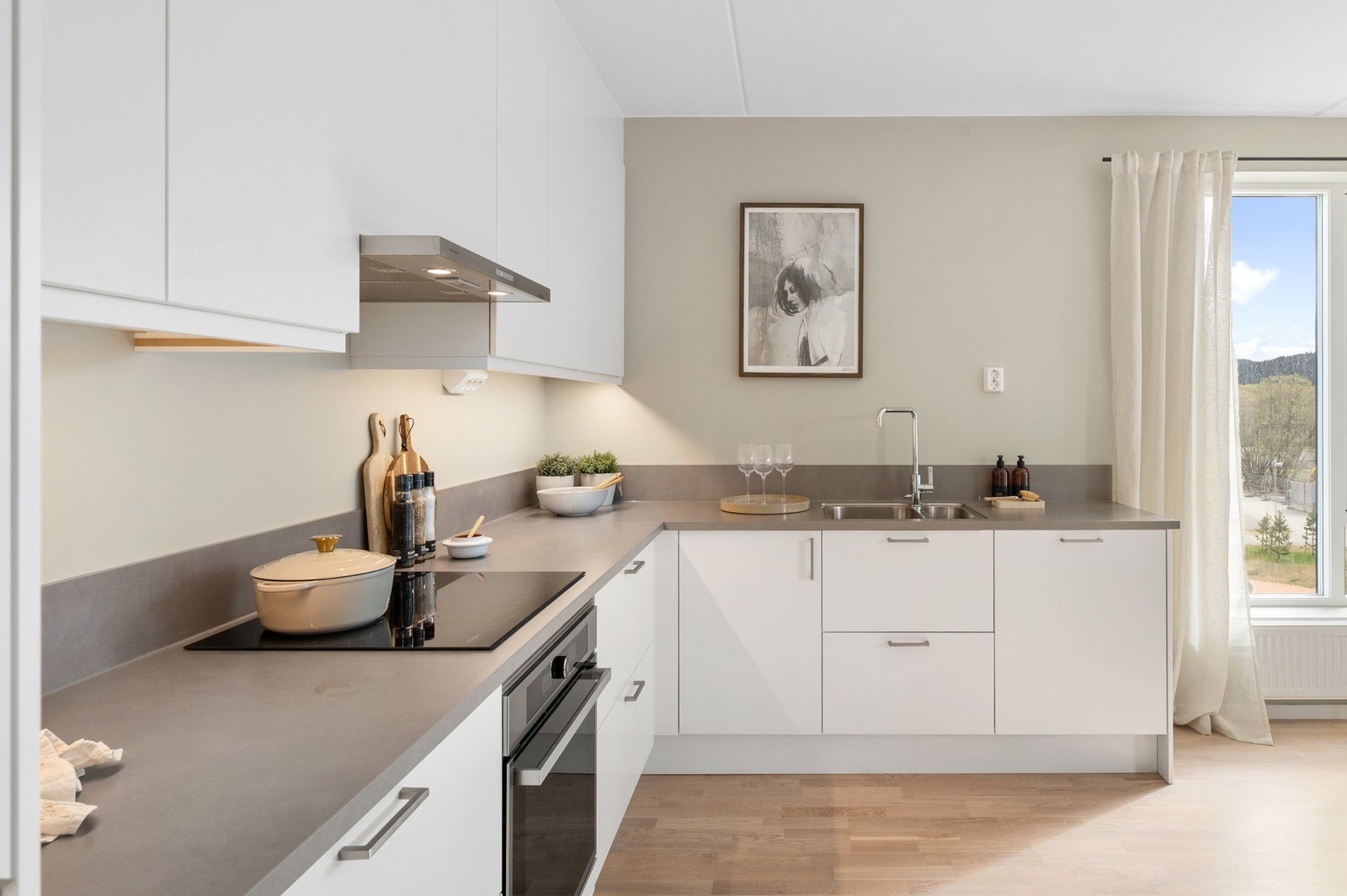 Kjøkkenet fremstår stilrent og funksjonelt med hvite slette fronter og laminert benkeplate. Galleribilde